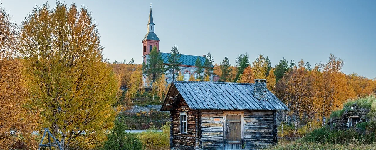 Vanha hirsitalo ja kirkontorni Utsjoella syksyn keltaisten puiden keskellä. Vanha hirsitalo ja kirkontorni Utsjoella syksyn keltaisten puiden keskellä.